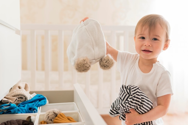 Free photo mid shot cute baby taking clothes from drawer