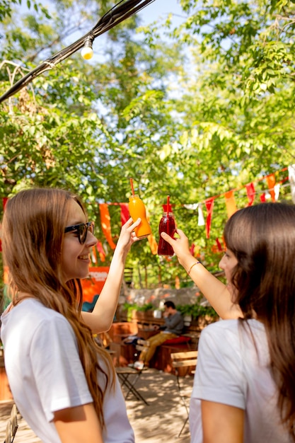 Free photo mid shot friends holding fresh juice bottles in park