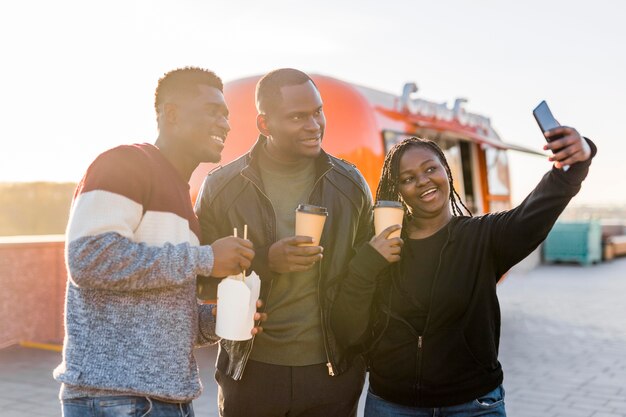 Mid shot friends near food truck taking selfie