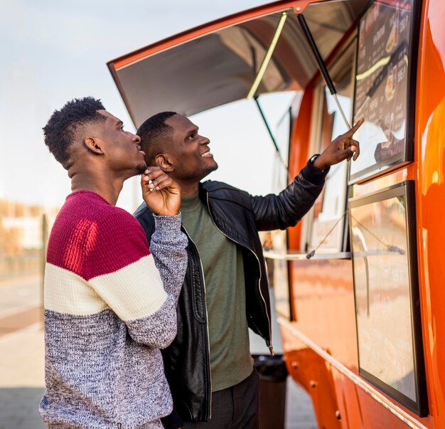 Mid shot men reading food truck menu