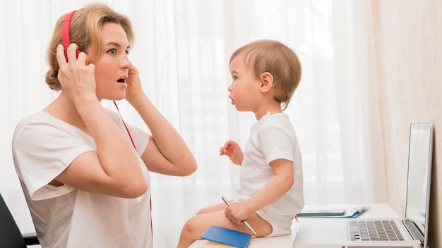 Mid shot mother with headphones and baby on desk