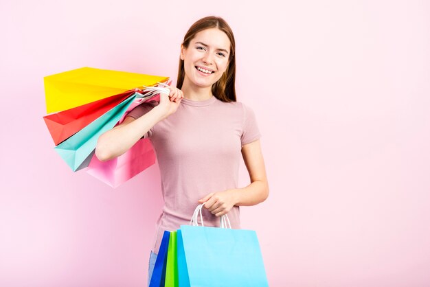 Mid shot smiling woman holding bags and looking at camera