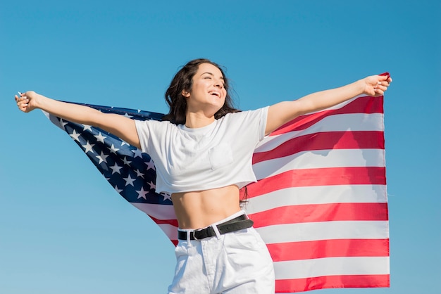 Free photo mid shot smiling woman holding big usa flag