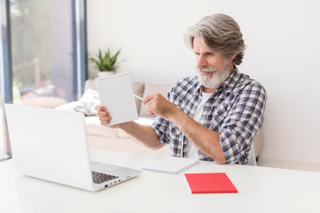 Mid shot teacher showing notebook at laptop