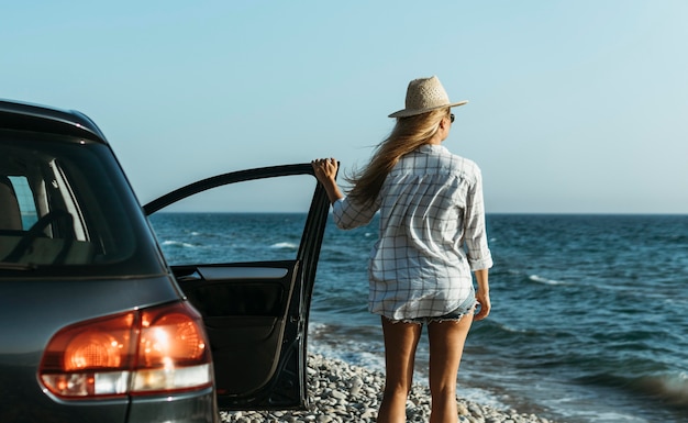 Mid shot woman looking at sea by car