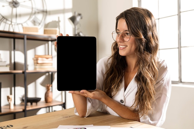 Free photo mid shot woman showing tablet