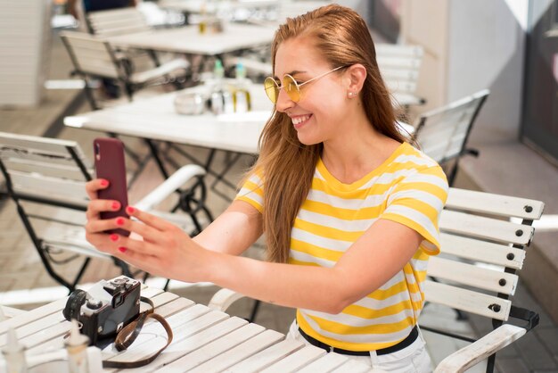 Mid shot woman at table taking selfie