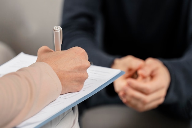 Mid shot woman therapist taking notes in clipboard