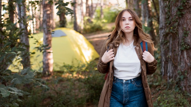 Free Photo mid shot woman with backpack in front of tent