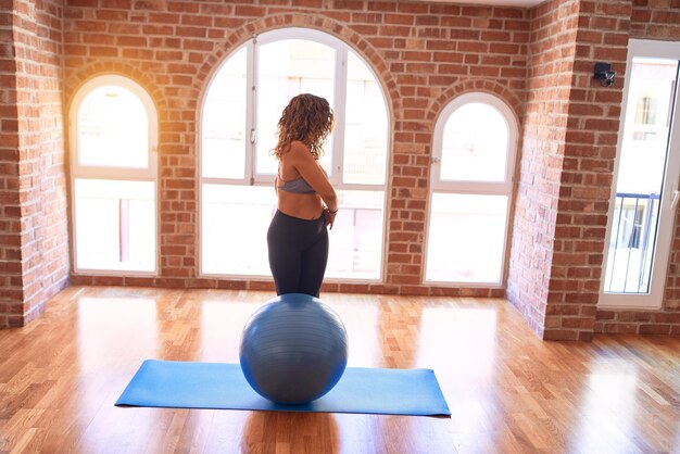 Middle age beautiful sportswoman doing exercise using fitness ball in a class of yoga at gym