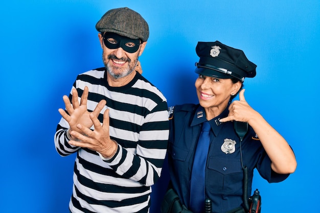 Free Photo middle age couple of hispanic woman and man wearing thief and police uniform smiling doing phone gesture with hand and fingers like talking on the telephone. communicating concepts.