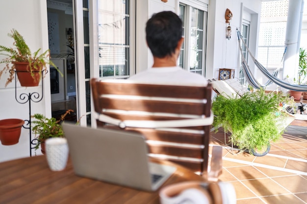 Free photo middle age man using computer laptop at home standing backwards looking away with crossed arms