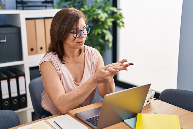 Middle age woman business worker suffering for wrist pain working at office