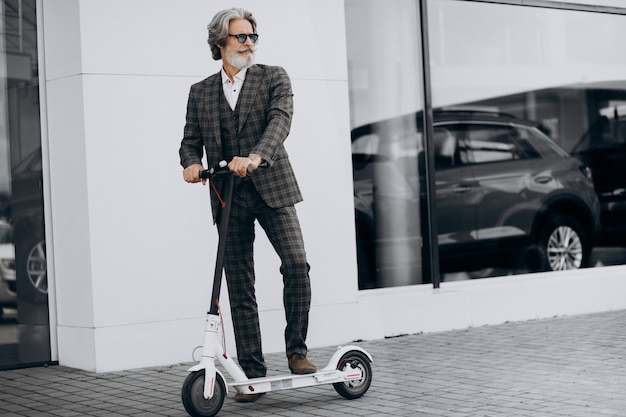 Middle aged business man riding scooter in a classy suit