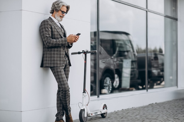 Free photo middle aged business man riding scooter in a classy suit