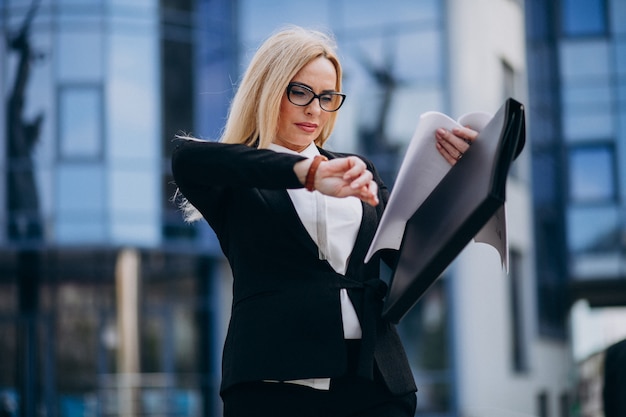 Middle aged business woman holding documents by the business center