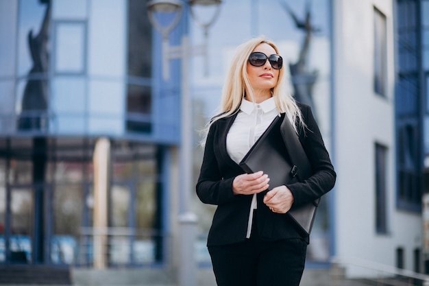 Free photo middle aged business woman with suitcase by bussiness center