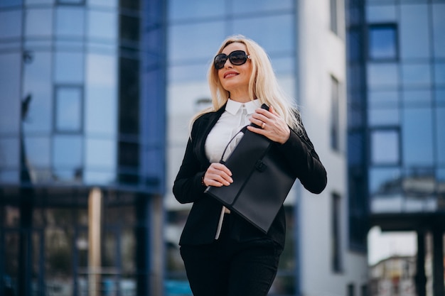 Free photo middle aged business woman with suitcase by bussiness center