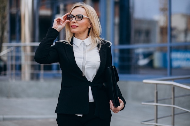 Free photo middle aged business woman with suitcase by bussiness center