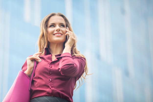 Free Photo middle-aged businesswoman smiling and communicating with her partners. young attractive smiling woman speaking over cell phone in the city.