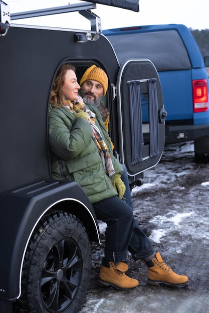 Free photo middle aged couple rest in camper smile good mood at winter vacation in the wild traveling across country mature couple rest in camper woman look with love on her husband journey concept