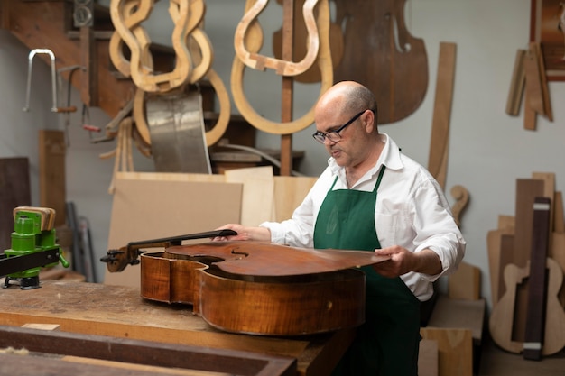 Free Photo middle aged man in his instrument workshop