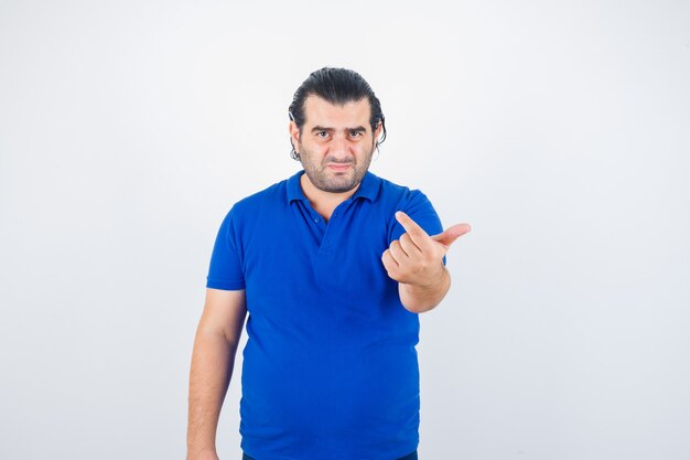 Middle aged man inviting to come in polo t-shirt and looking troubled , front view.