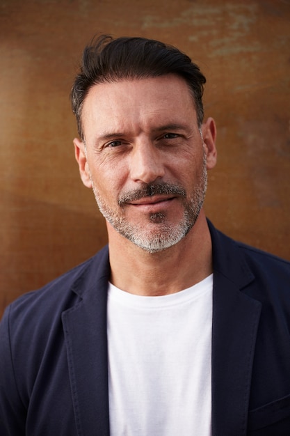 Middle-aged man wearing leaning against a rusty colored background