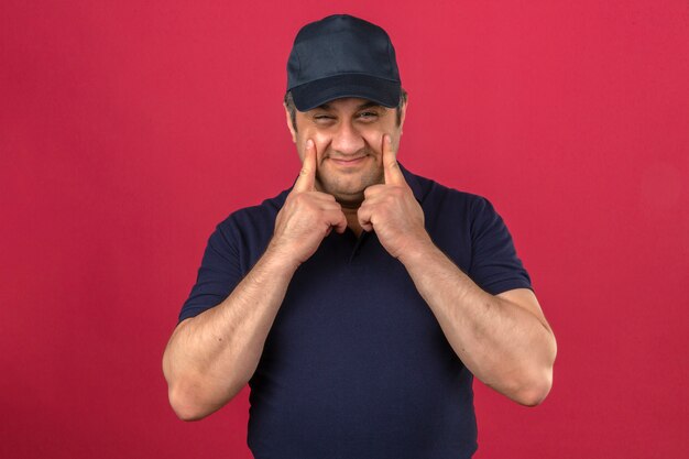 Free Photo middle aged man wearing polo shirt and cap pointing his eyes and smiling over isolated pink wall