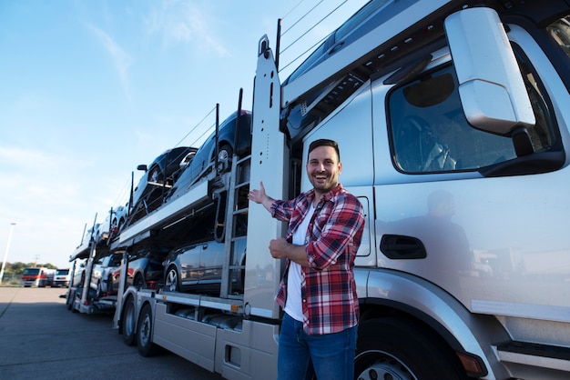 Middle aged trucker in front of truck trailer with cars