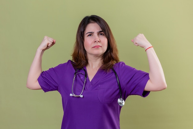 Middle aged woman nurse wearing uniform and with stethoscope looking confident self-satisfied rejoicing her success