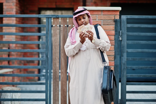 Middle Eastern arab business man posed on street against modern building with black handbag and euro moneys