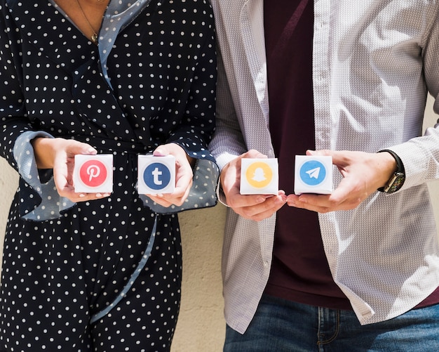 Free photo midsection of a couple holding boxes of social media icons