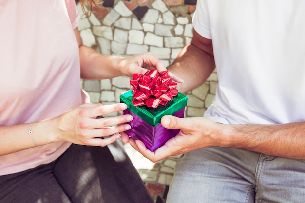 Free photo midsection view of a couple's hand holding gift box