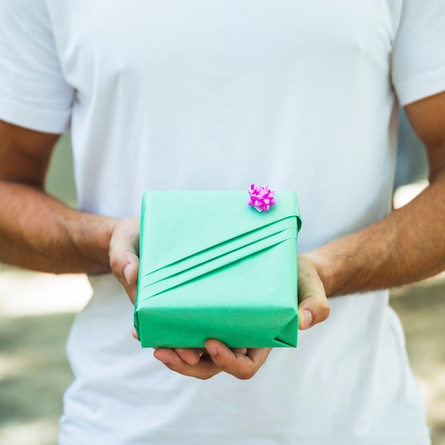 Free Photo midsection view o a man's hand holding green gift box