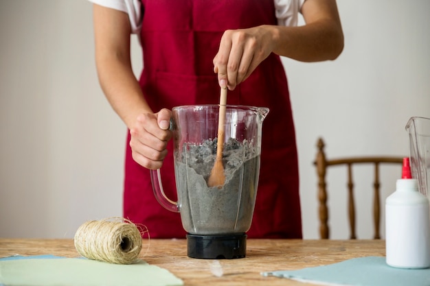 Free Photo midsection view of a woman's hand stirring paper pulp in blender