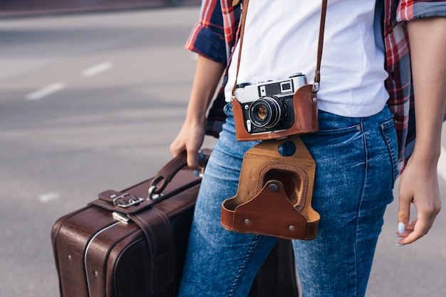 Free Photo midsection of young woman traveler carrying luggage bag on street