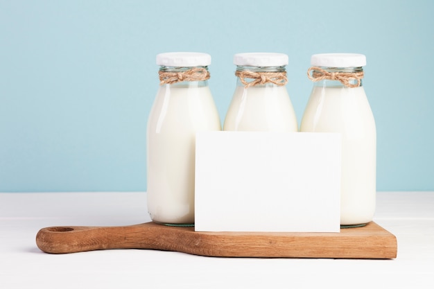 Milk bottles and card on chopping board