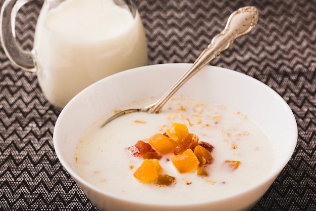 Milk bowl with fruits toppings on tablecloth