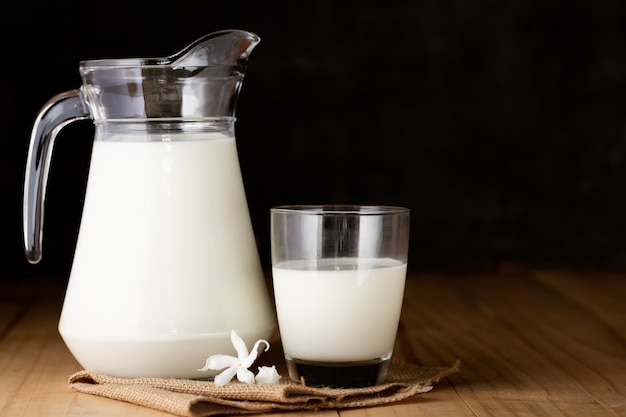 milk in glass and jug on wooden table