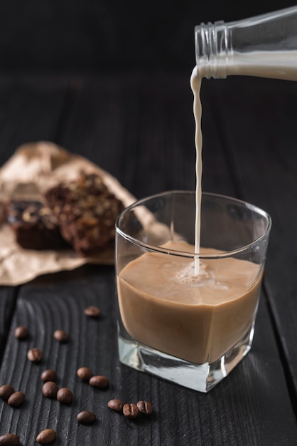 Free photo milk poured from bottle in glass of coffee