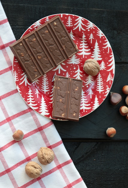 Free photo milky chocolate with nuts in a red plate on the wooden table.