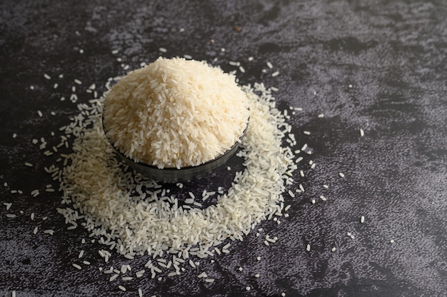 Free Photo milled rice in a black bowl on the black cement floor.