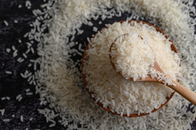 Free photo milled rice in a bowl and a wooden spoon on the black cement floor.