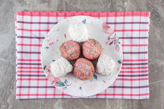 Free Photo mini cakes and turkish cotton candy in a plate on tea towel on blue.