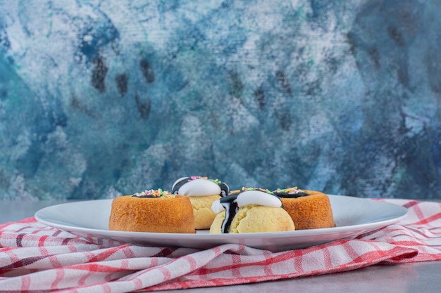 Free Photo mini cakes with jelly and biscuits on white plate.