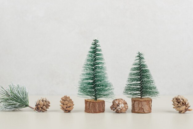 Free Photo mini christmas trees and pinecones on beige surface