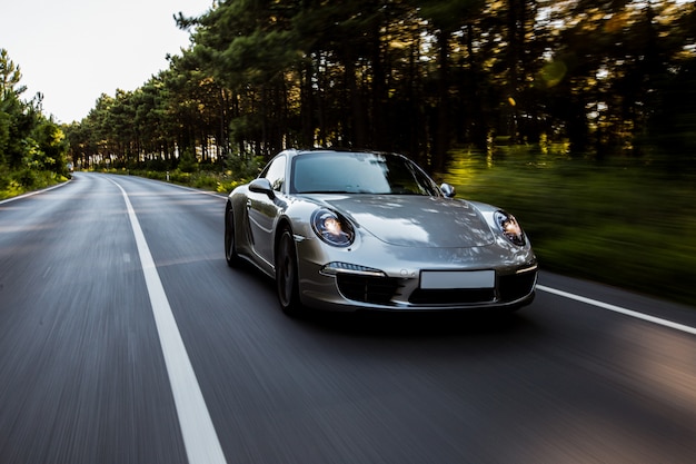 Mini coupe high speed drive on the road with front lights on.