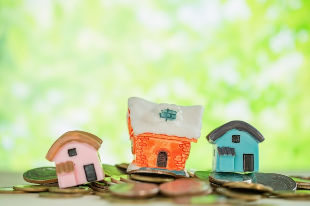 Free Photo mini house on pile of coins with green blur. 