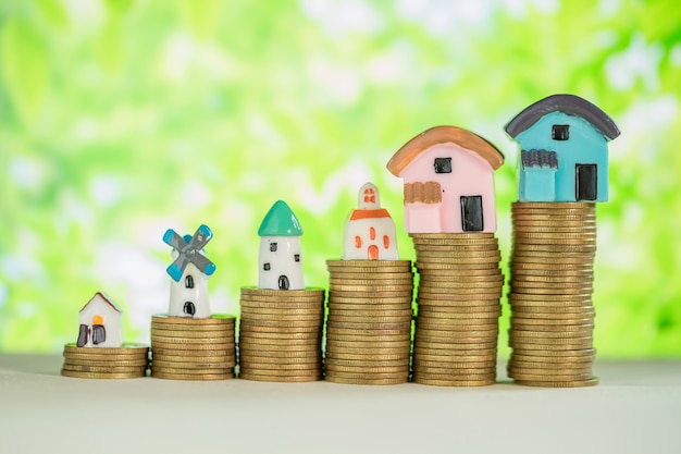 Free photo mini house on stack of coins with green blur.